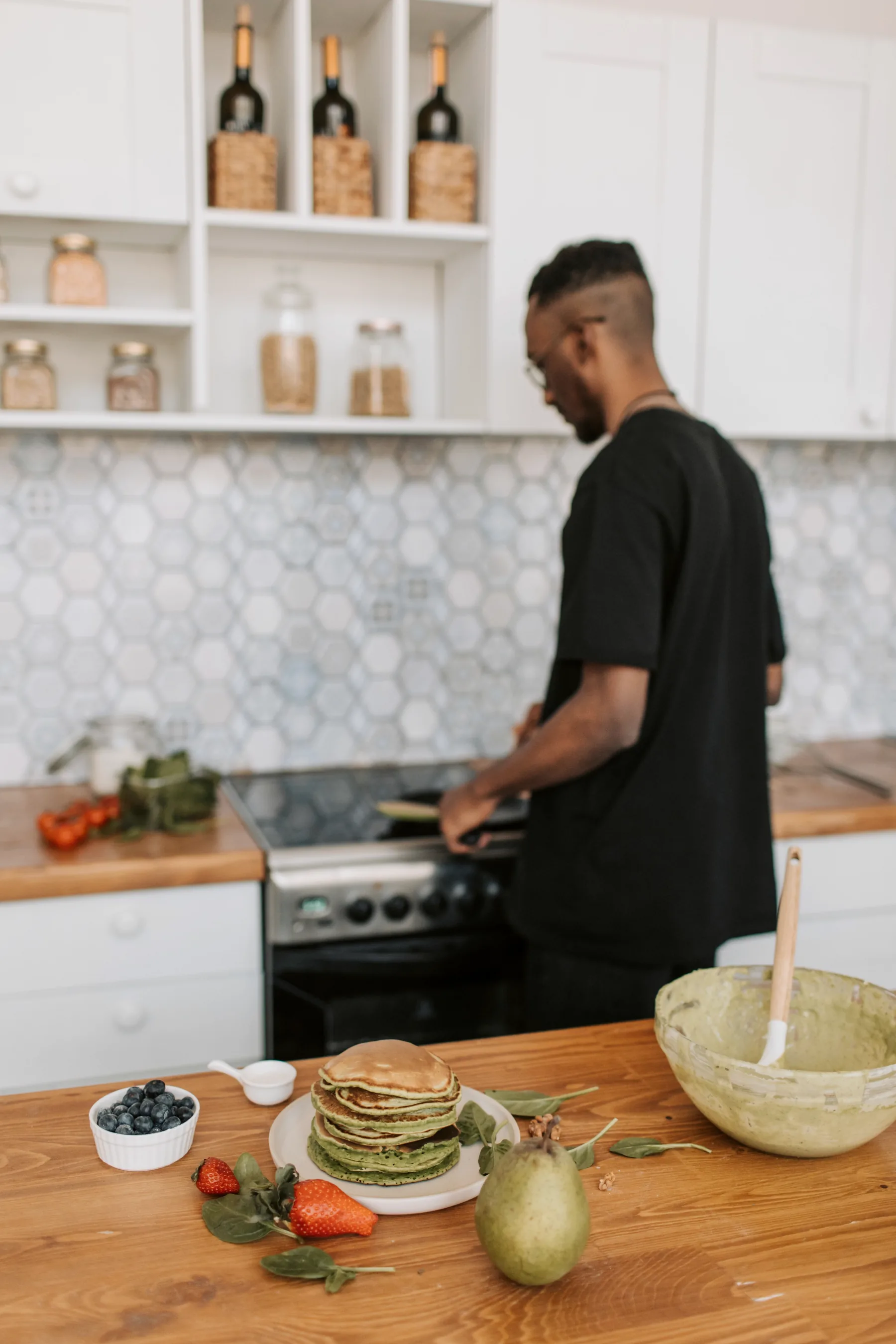 Hombre preparando un desayuno con fruta y alimentos frescos en una cocina luminosa